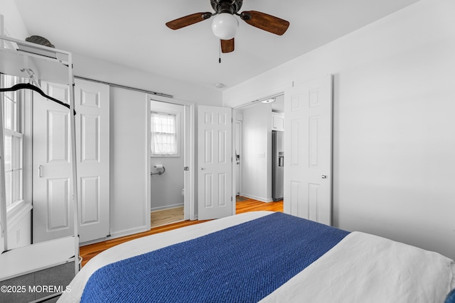 bedroom with stainless steel refrigerator with ice dispenser, a closet, ceiling fan, and light wood-type flooring