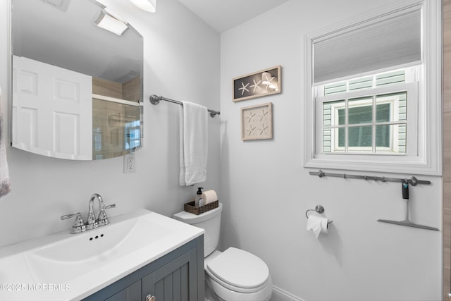 bathroom featuring a shower with shower door, vanity, and toilet