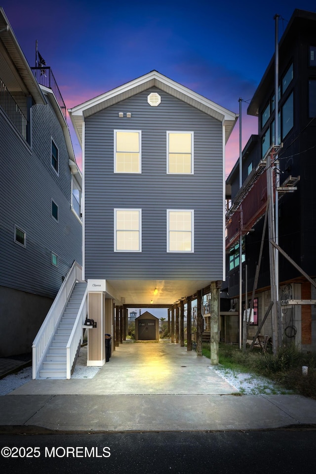 back house at dusk featuring a carport