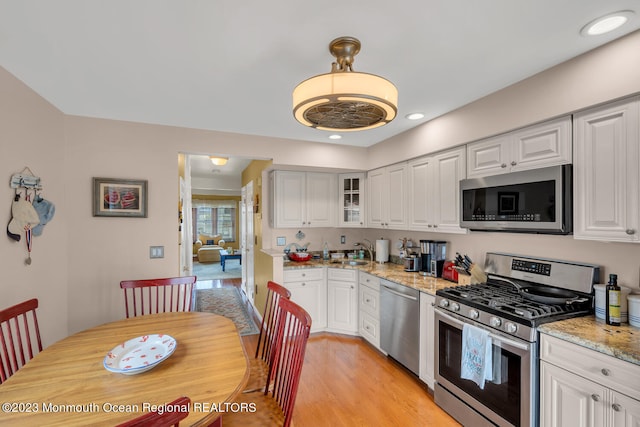 kitchen with white cabinets, appliances with stainless steel finishes, and light stone countertops