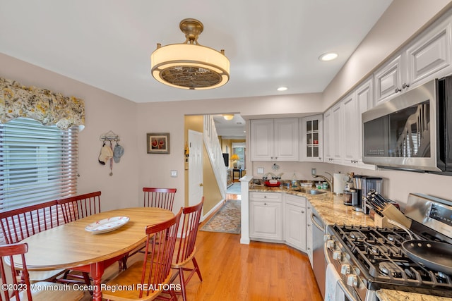 kitchen featuring light stone counters, light hardwood / wood-style flooring, stainless steel appliances, white cabinets, and sink