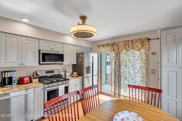 kitchen featuring gray cabinets, light stone counters, and appliances with stainless steel finishes