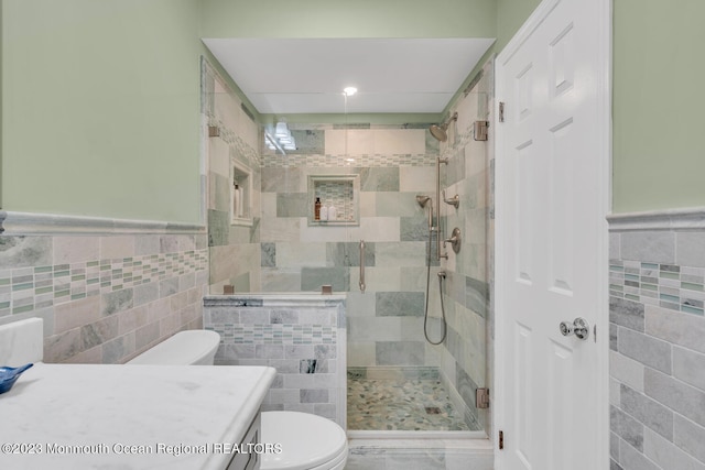 bathroom featuring toilet, an enclosed shower, vanity, and tile walls