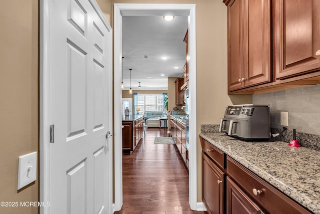 kitchen featuring tasteful backsplash, dark hardwood / wood-style flooring, and light stone counters