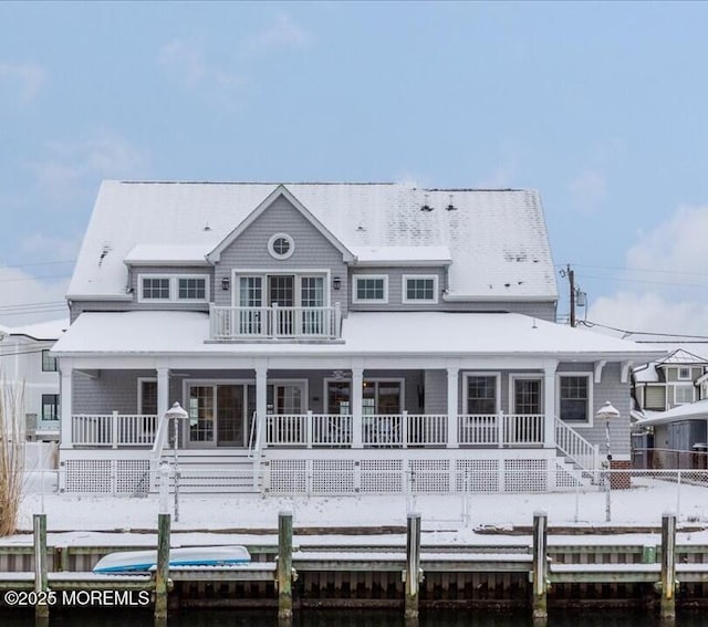 back of property featuring covered porch and a balcony