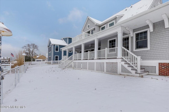 snow covered back of property featuring covered porch