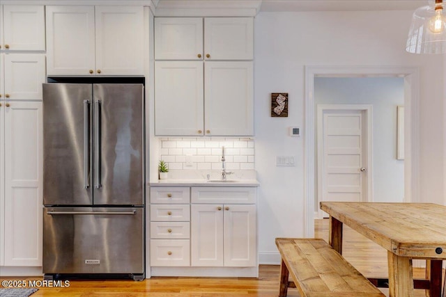 kitchen with high quality fridge, sink, decorative backsplash, and white cabinetry