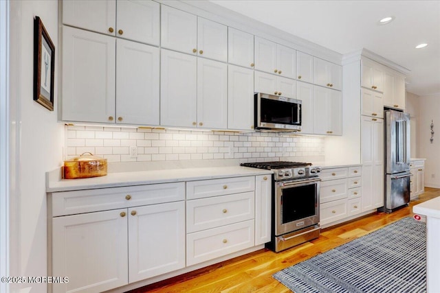 kitchen featuring stainless steel appliances, white cabinets, light wood-type flooring, and backsplash