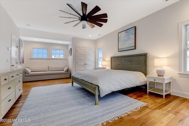 bedroom featuring light wood-type flooring, ceiling fan, and multiple windows