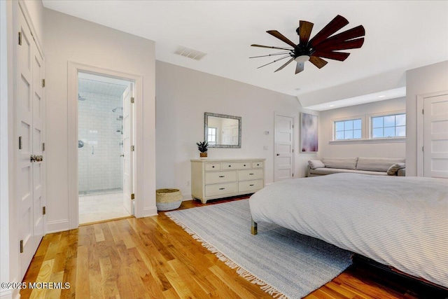 bedroom featuring ceiling fan, light hardwood / wood-style floors, and ensuite bath