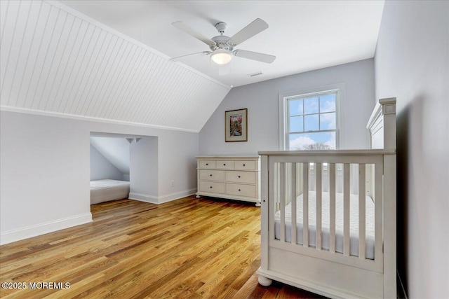 bedroom with ceiling fan, vaulted ceiling, and light wood-type flooring