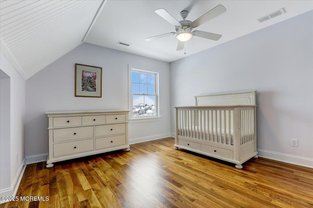 unfurnished bedroom featuring light hardwood / wood-style floors, ceiling fan, lofted ceiling, and a nursery area