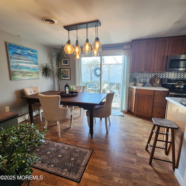 dining area featuring baseboard heating and light hardwood / wood-style flooring