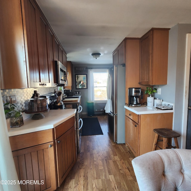 kitchen with appliances with stainless steel finishes, light hardwood / wood-style floors, and tasteful backsplash