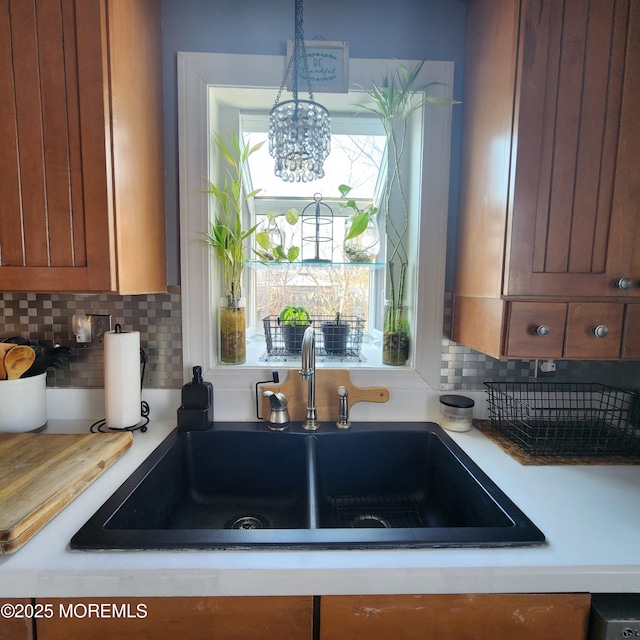 kitchen with sink, pendant lighting, an inviting chandelier, and tasteful backsplash