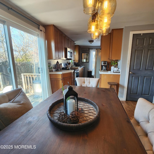 kitchen featuring backsplash, hardwood / wood-style floors, an inviting chandelier, hanging light fixtures, and appliances with stainless steel finishes