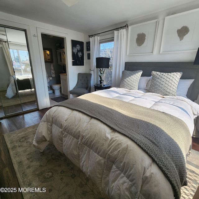 bedroom with ensuite bathroom and dark hardwood / wood-style floors