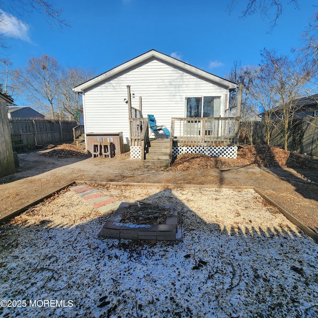 back of house with a deck and a fire pit