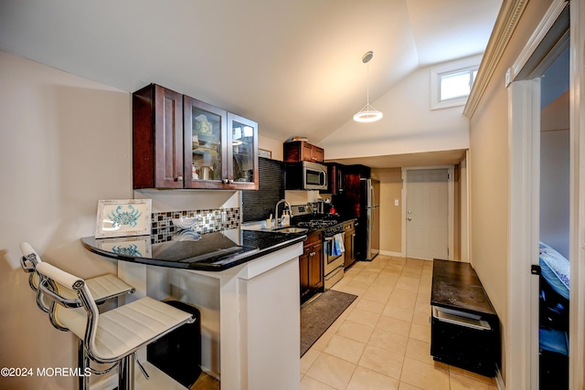 kitchen with lofted ceiling, tasteful backsplash, a breakfast bar, light tile patterned flooring, and appliances with stainless steel finishes