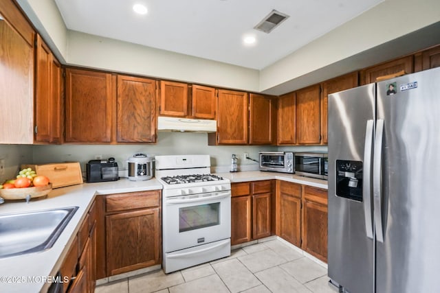 kitchen with stainless steel appliances, light tile patterned floors, and sink