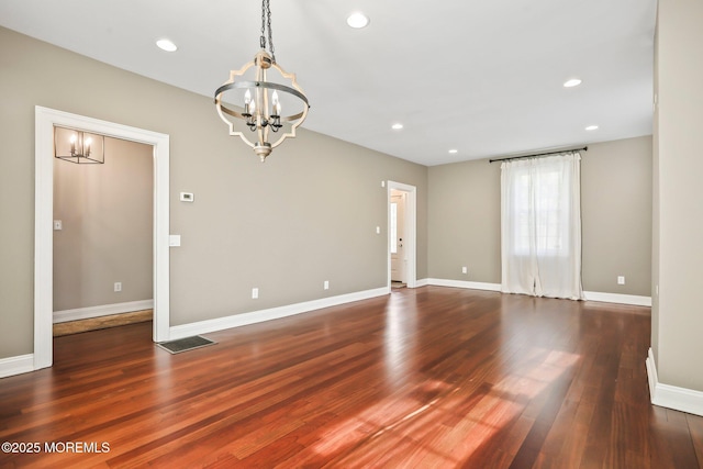 spare room featuring a notable chandelier and dark hardwood / wood-style floors