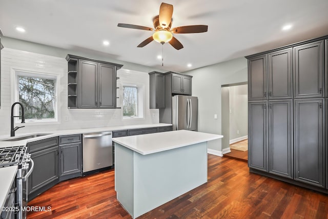 kitchen featuring stainless steel appliances, a center island, sink, and gray cabinetry