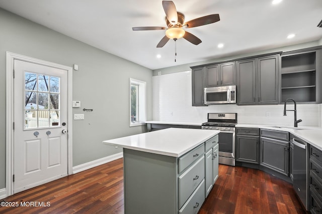 kitchen featuring appliances with stainless steel finishes, gray cabinetry, a center island, ceiling fan, and tasteful backsplash