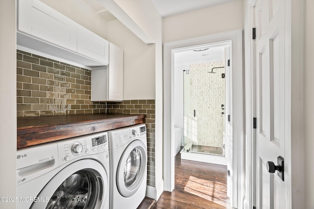 clothes washing area with dark hardwood / wood-style flooring, cabinets, and independent washer and dryer