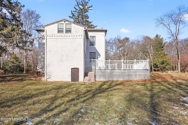 back of property featuring a deck and a lawn