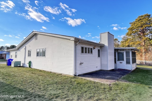 rear view of property featuring a lawn, a patio area, and a sunroom