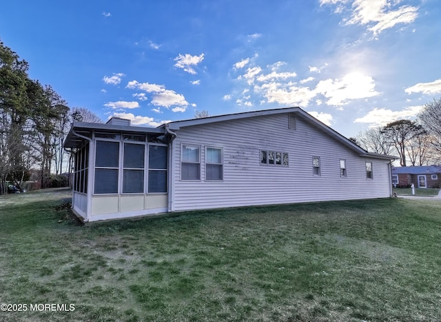 rear view of property featuring a yard and a sunroom