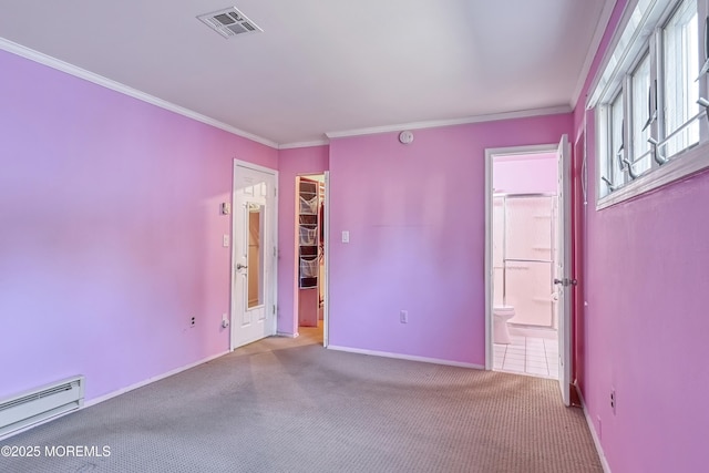 unfurnished bedroom with ensuite bath, a closet, a baseboard heating unit, carpet, and a walk in closet