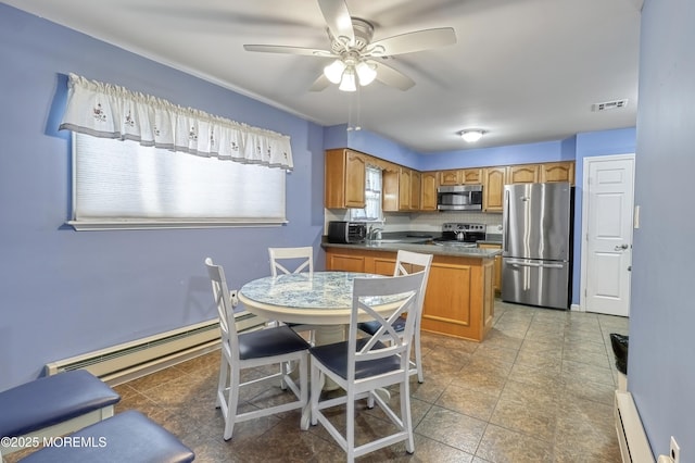 kitchen featuring a baseboard heating unit, appliances with stainless steel finishes, ceiling fan, and backsplash