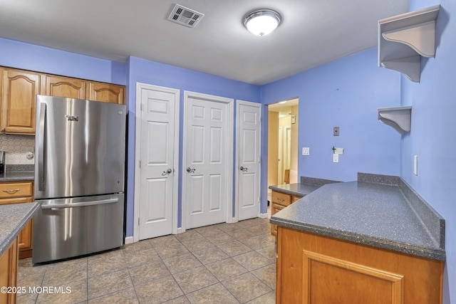 kitchen featuring tile patterned flooring, decorative backsplash, and stainless steel fridge