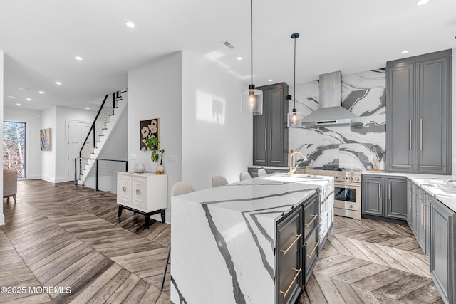 kitchen with backsplash, gray cabinets, pendant lighting, sink, and island exhaust hood