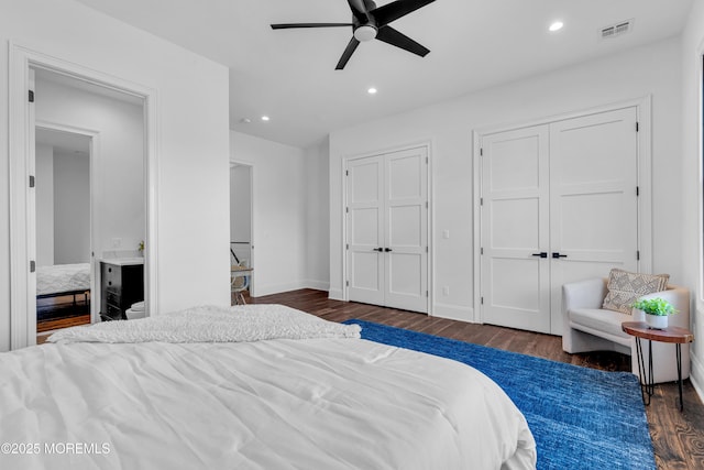 bedroom with ceiling fan, multiple closets, and dark hardwood / wood-style flooring