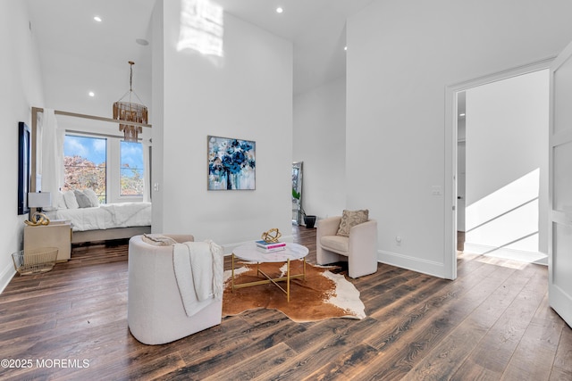 sitting room with a towering ceiling and dark hardwood / wood-style flooring