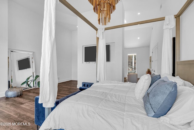 bedroom featuring hardwood / wood-style floors, lofted ceiling, and a notable chandelier