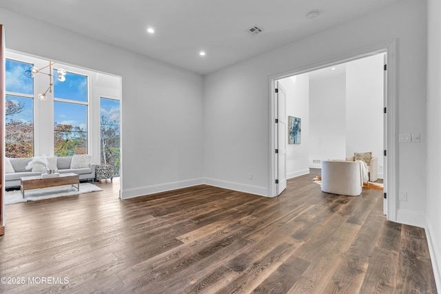 empty room with dark wood-type flooring and an inviting chandelier