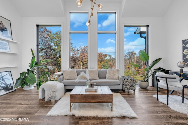 living room with dark hardwood / wood-style floors, lofted ceiling, and an inviting chandelier