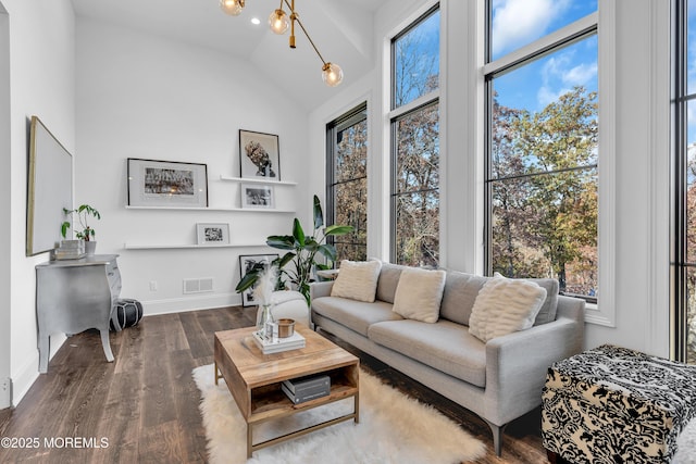 living room featuring wood-type flooring, a towering ceiling, and a chandelier