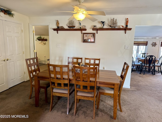 dining space with ceiling fan and dark colored carpet