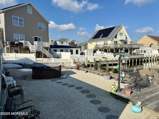 back of property with cooling unit, a hot tub, a patio, and a deck with water view