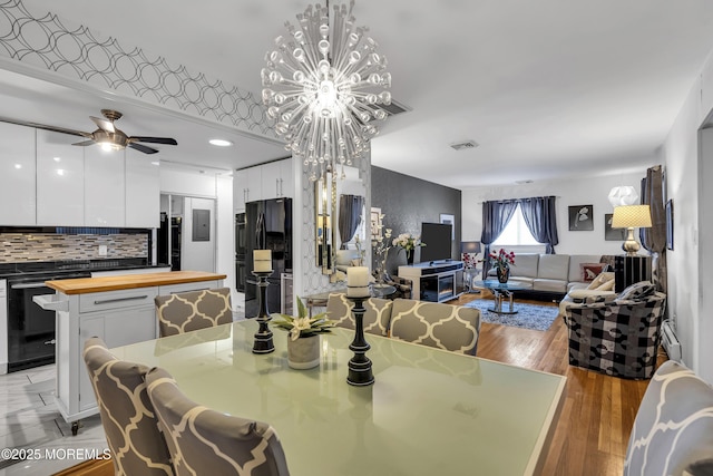 dining space featuring wood-type flooring and ceiling fan with notable chandelier