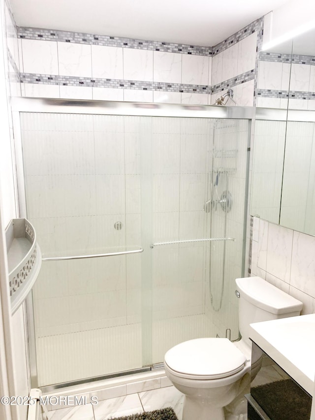 bathroom featuring vanity, toilet, tile walls, and walk in shower