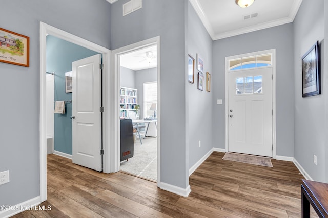 entryway with ceiling fan, crown molding, and wood-type flooring