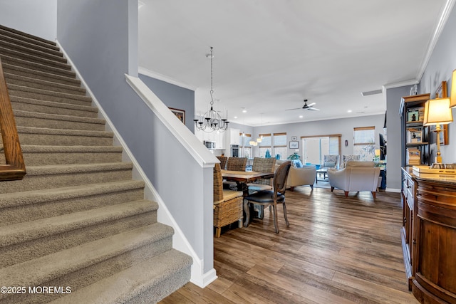 stairs with ceiling fan with notable chandelier, hardwood / wood-style flooring, and crown molding