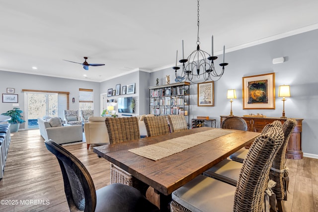 dining room featuring ceiling fan with notable chandelier, light wood-type flooring, and crown molding