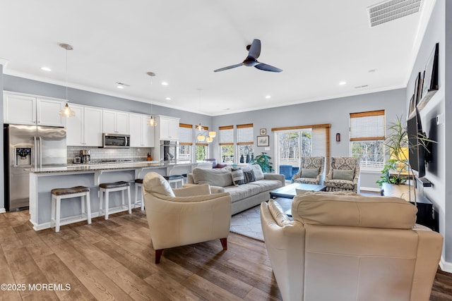 living room featuring ceiling fan, light wood-type flooring, and crown molding