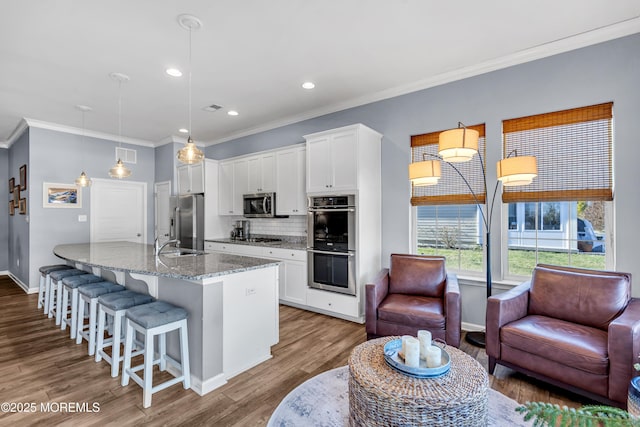 kitchen featuring stainless steel appliances, white cabinets, hanging light fixtures, and light stone countertops